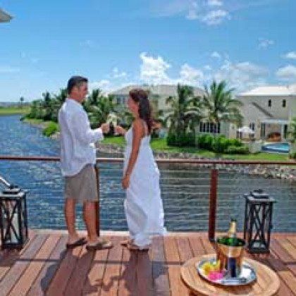 A man and a woman are standing on a deck overlooking a body of water.