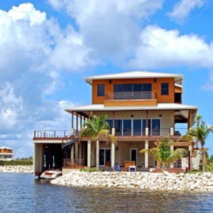 A large house sits on a small island in the middle of a body of water