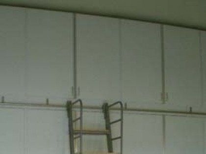 A ladder is hanging from the ceiling in a room with white cabinets.