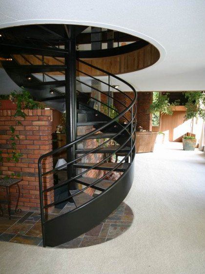 A spiral staircase in a house with a black railing
