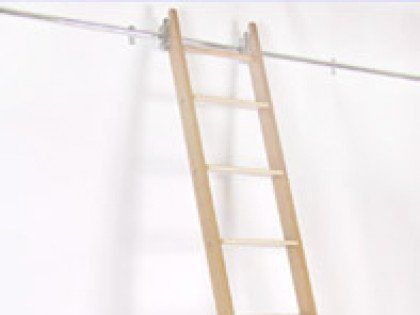 A wooden ladder is hanging from a metal railing on a white wall.
