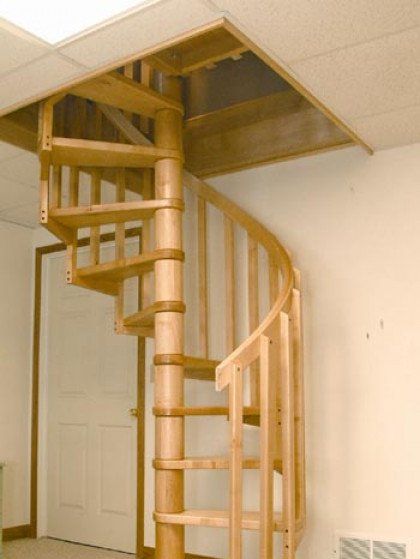 A wooden spiral staircase in a room with white walls