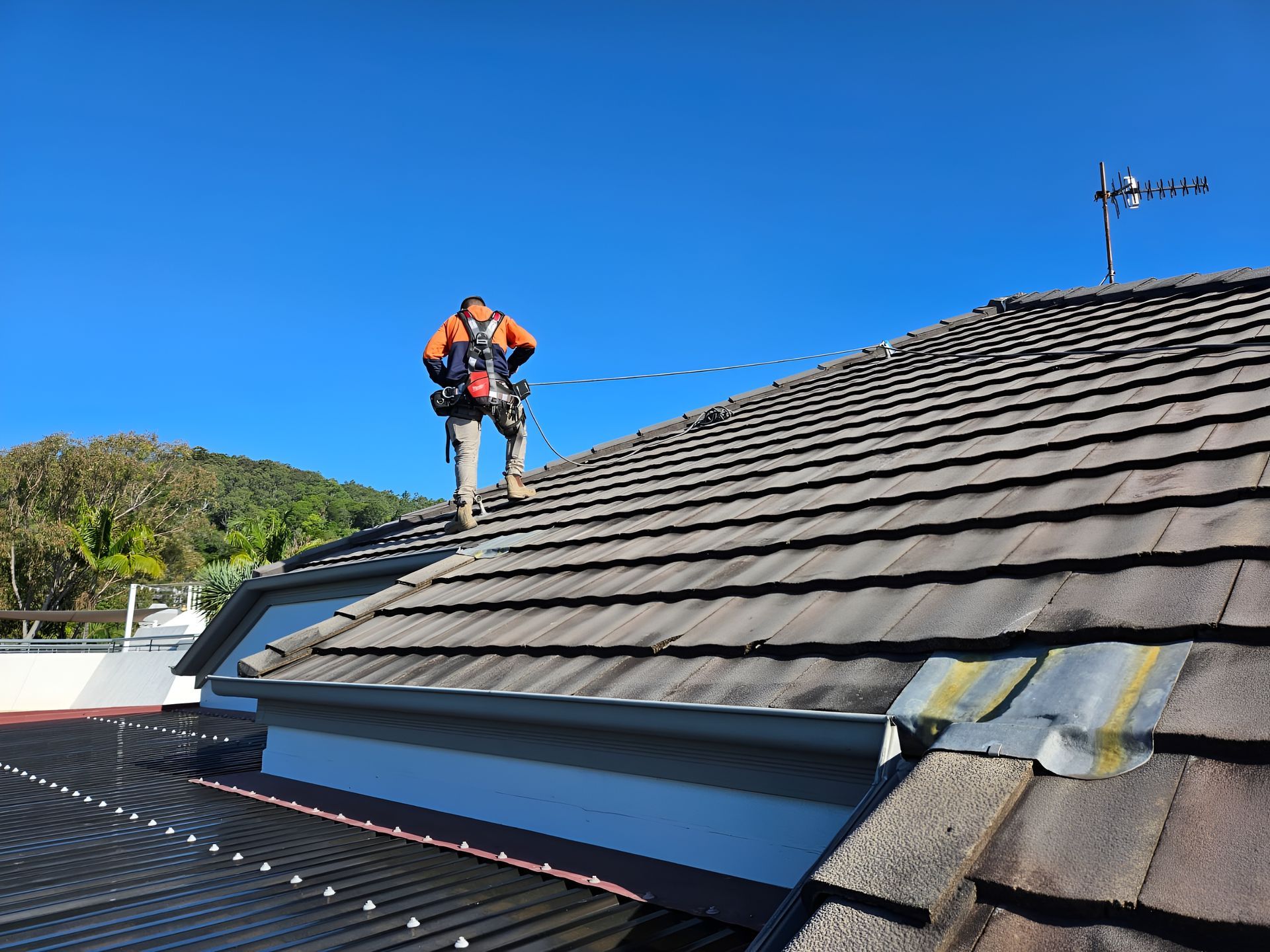 Roofer in Orange Safety Vest and Harness — Australian Asset Compliance in Mackay, QLD