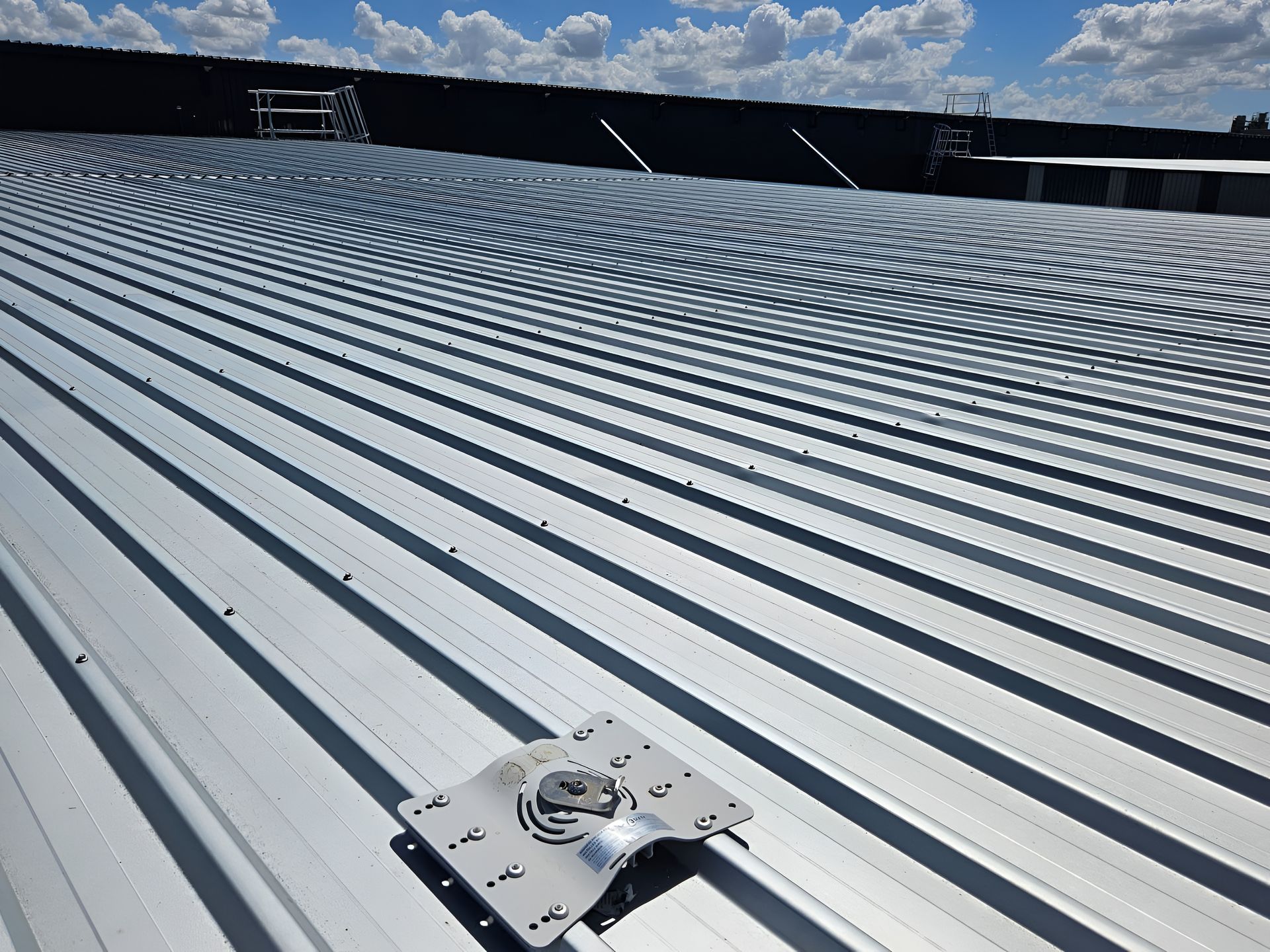 Metal roof with a mounting bracket, set against a blue sky with clouds. — Australian Asset Compliance in Gold Coast, QLD