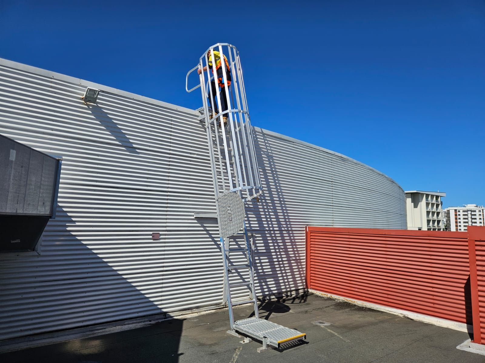 Metal access ladder on a building exterior with a person in a safety harness. — Australian Asset Compliance in Mackay, QLD