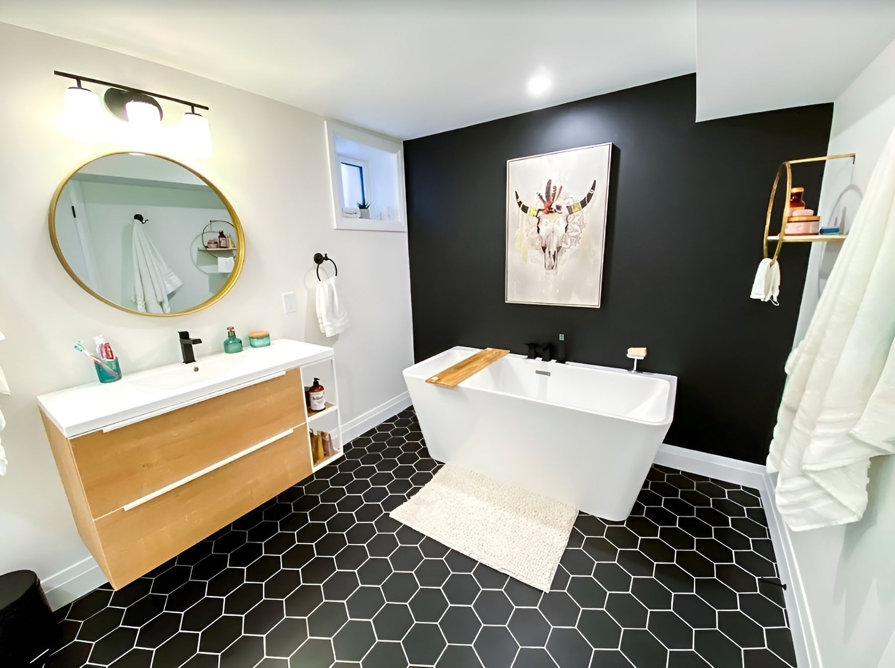 Modern bathroom with black hexagon tile, a white freestanding tub, and black accent wall.