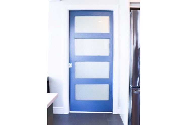 Blue interior door with four frosted glass panels, set in white frame.