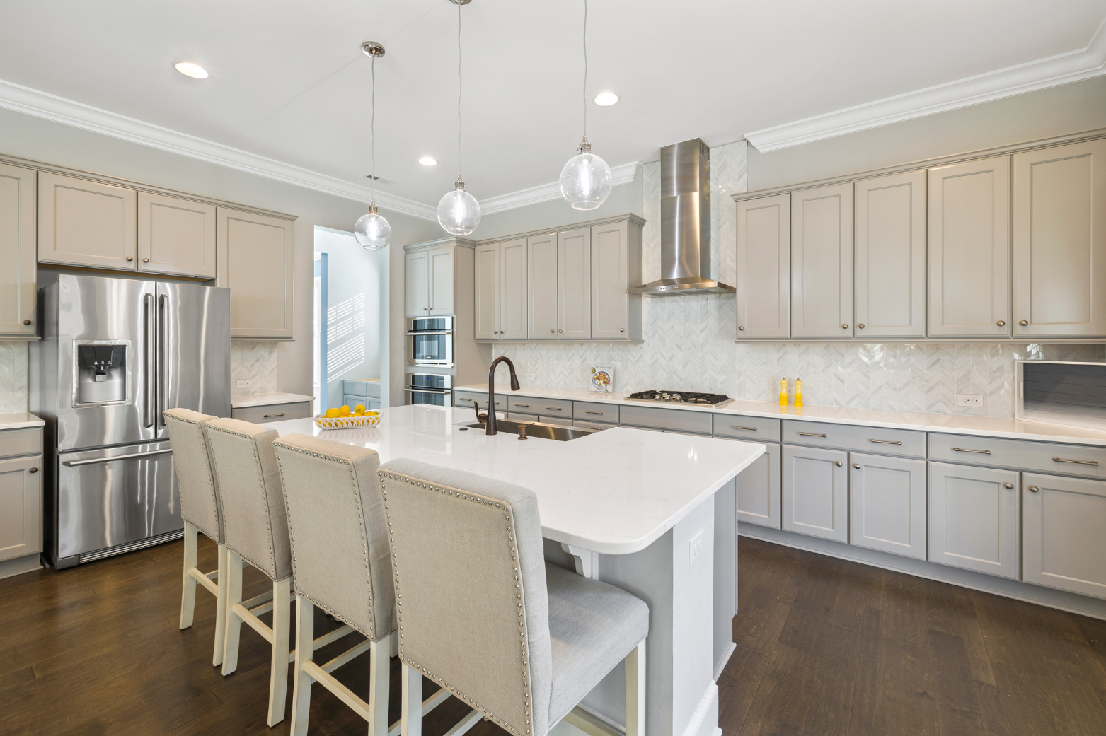 Modern kitchen with light gray cabinets, white island with seating, stainless steel appliances.
