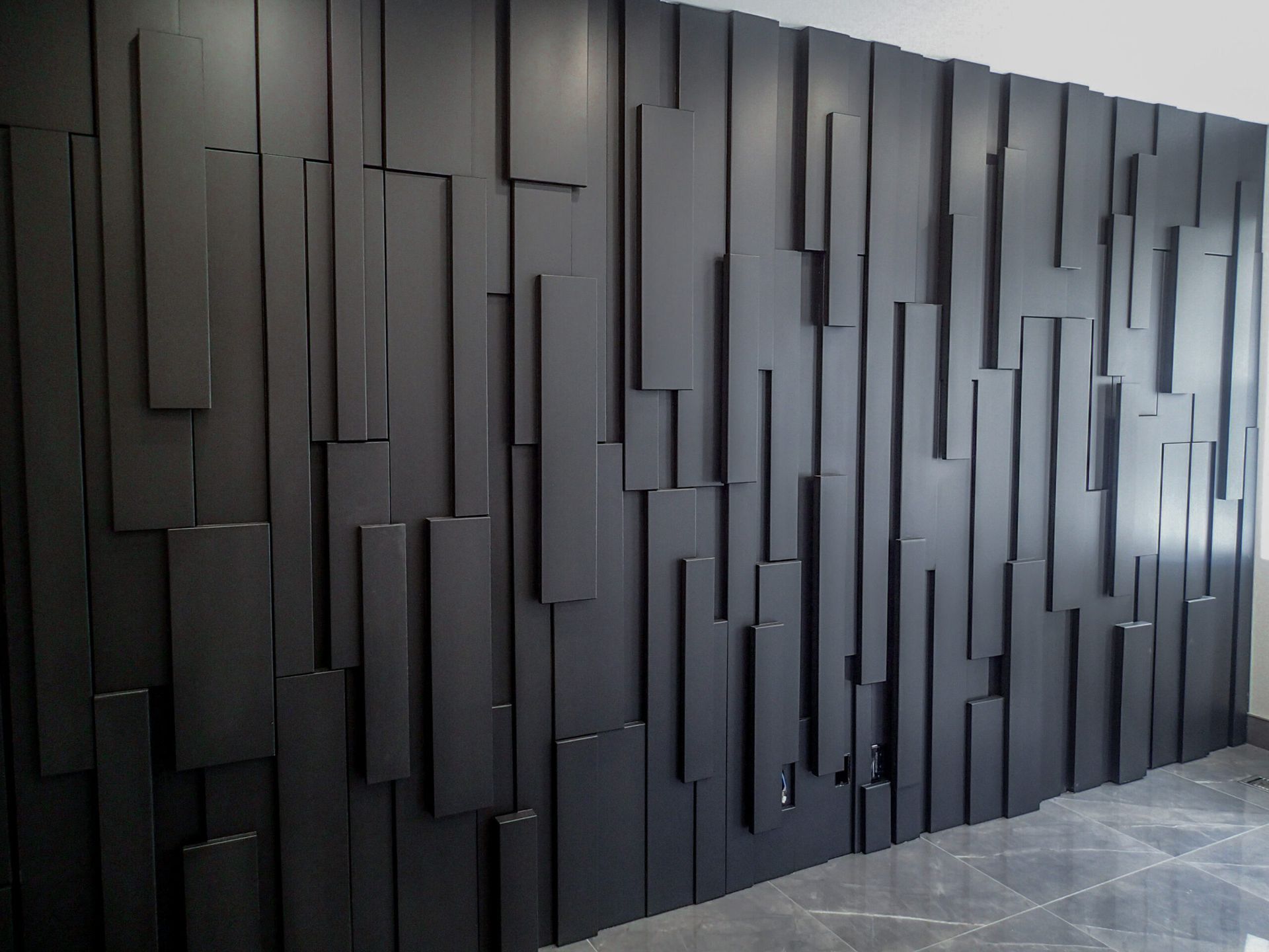 Black wall art with various rectangular shapes jutting out, creating a textured surface.