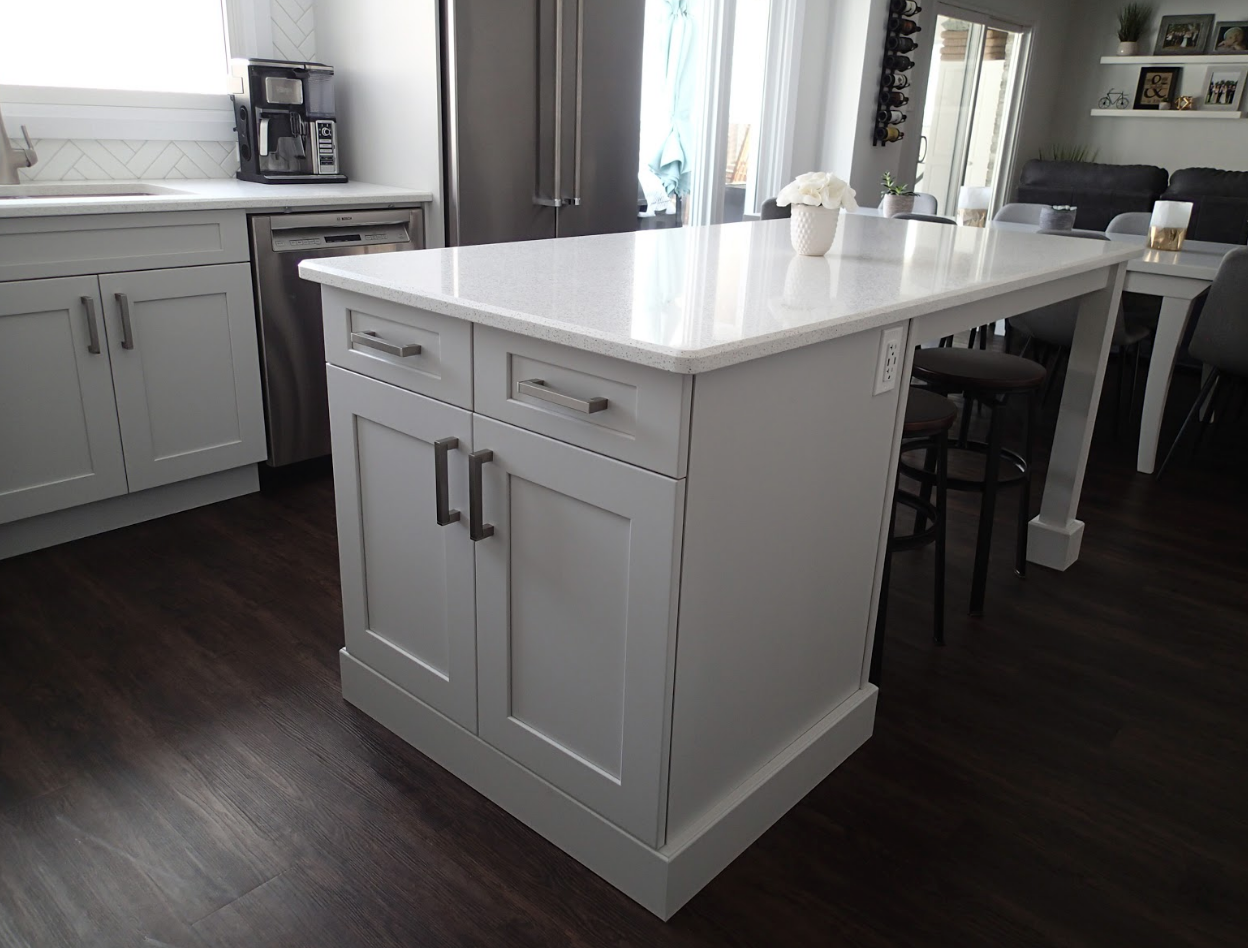 White kitchen island with cabinets and a countertop extension, a kitchen with dark floors.