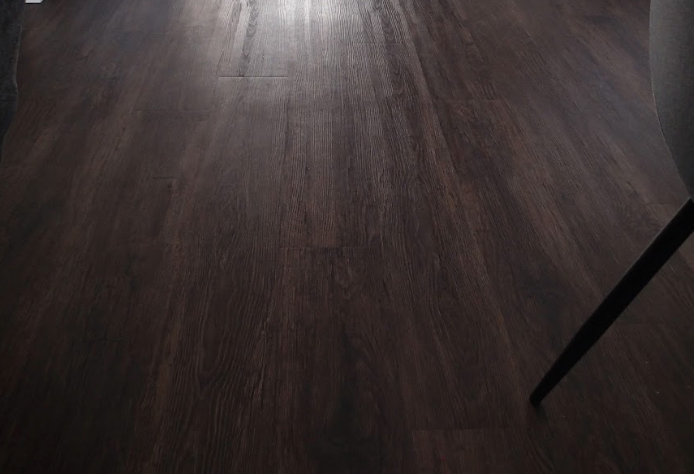 Dark brown wooden floor with a chair leg in the corner.