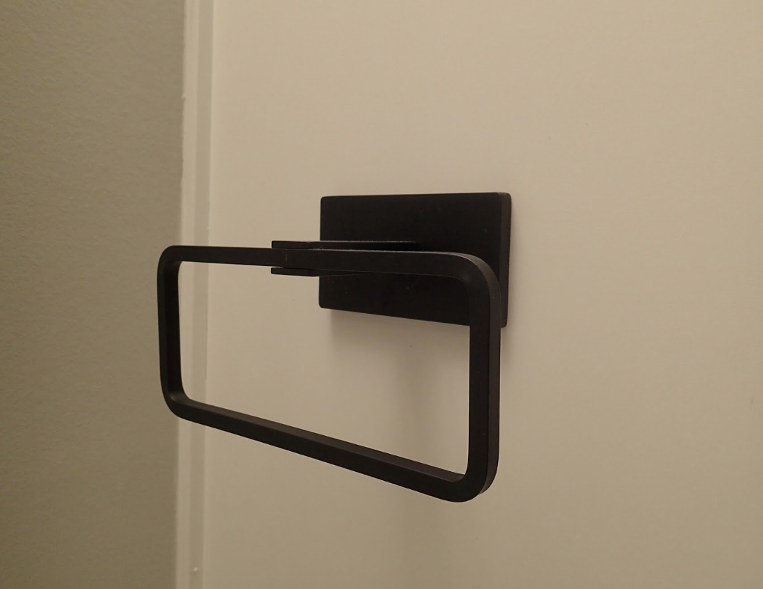 Black towel ring mounted on a white wall.