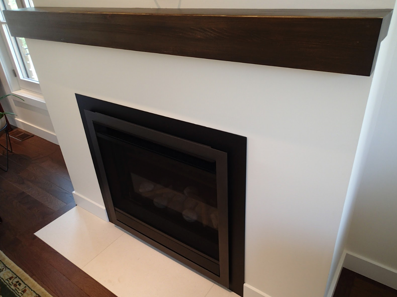 Fireplace with dark wood mantel, white surround, and black trim.