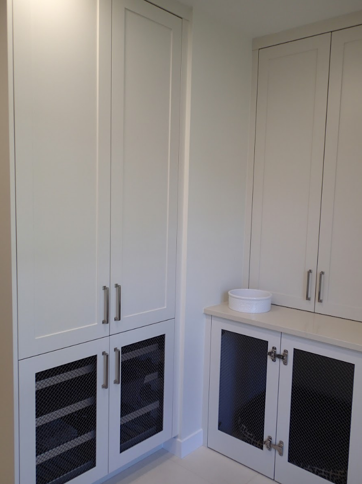 White cabinets with mesh-covered doors in a room, next to a small countertop with a bowl on it.