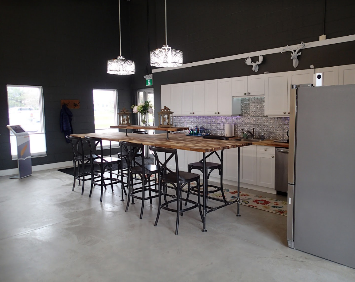 Modern kitchen with long wood island, black stools, white cabinets, and dark gray walls.