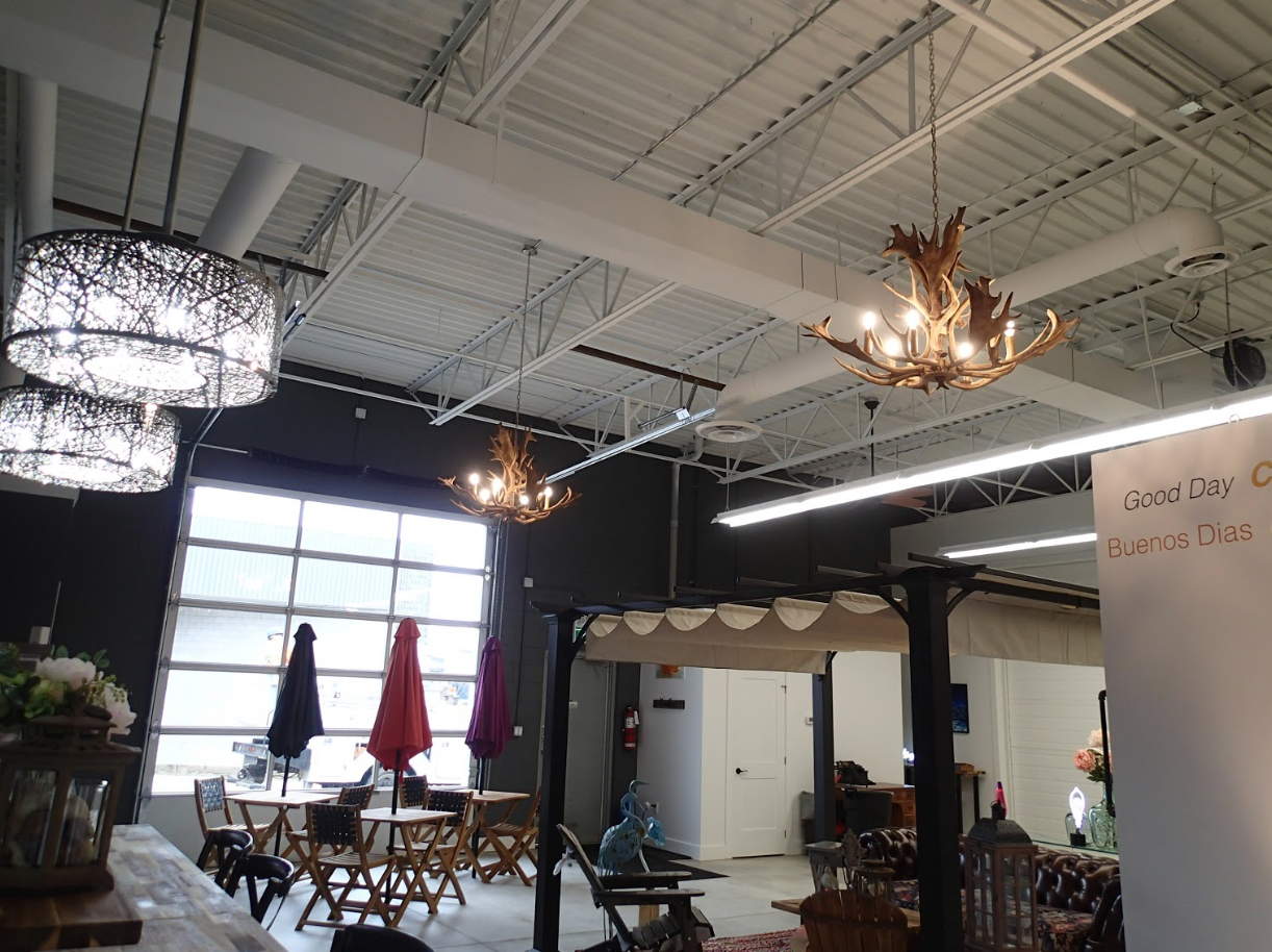 Indoor furniture showroom with chandeliers, patio sets, and a dark wall.