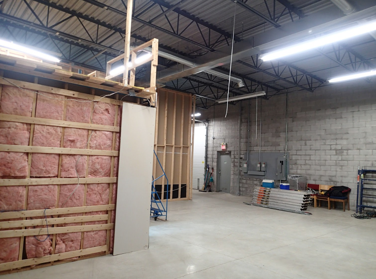Interior view of a construction site, with wooden frame walls, insulation, and exposed ceilings.