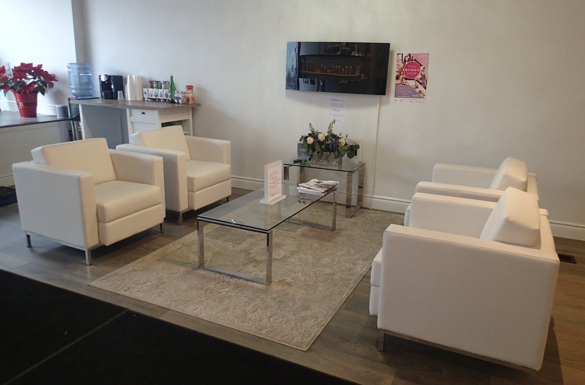 Waiting room with white chairs, glass coffee table, fireplace, and water cooler.