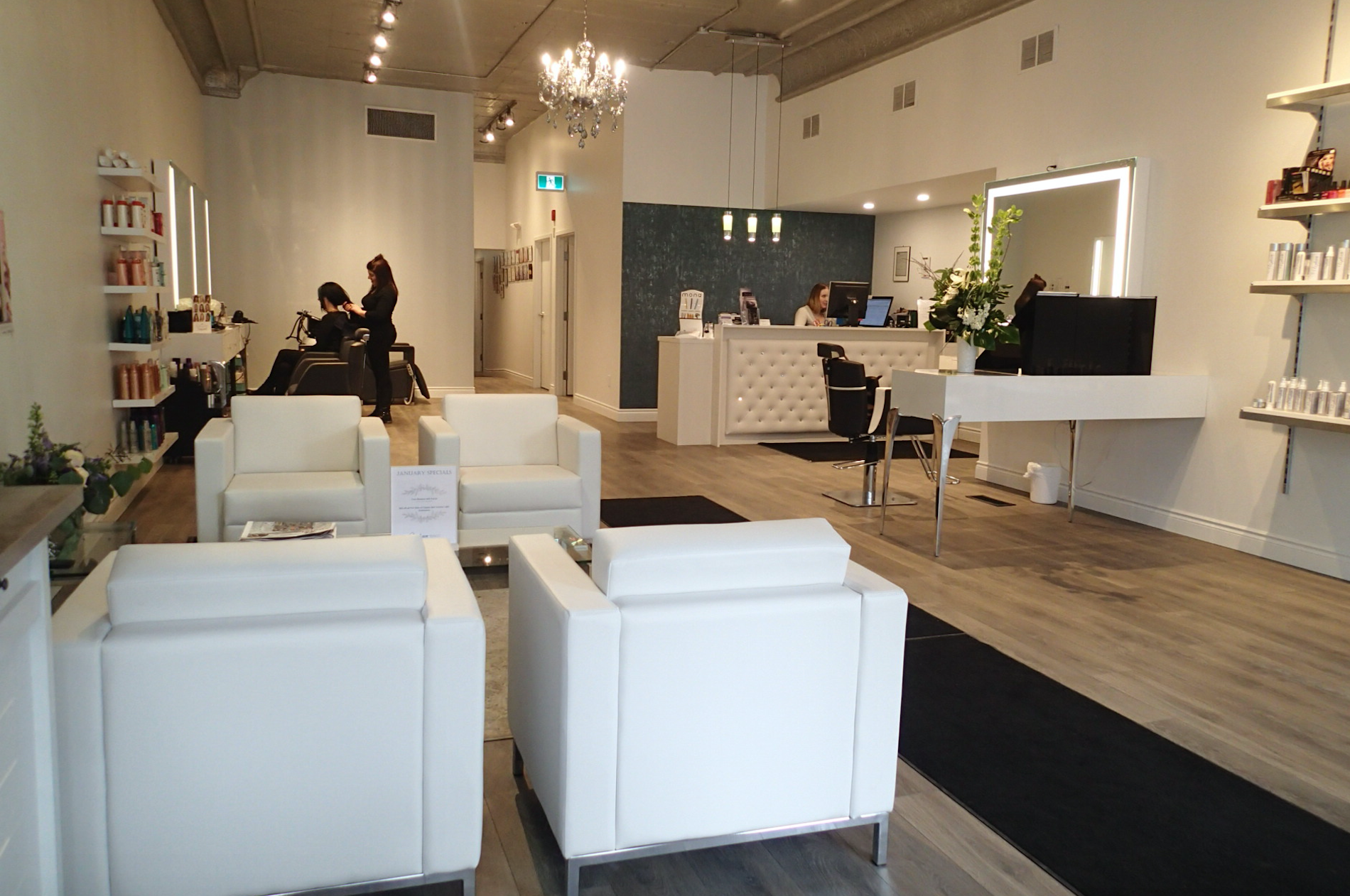 Salon interior with white chairs, reception, and stylists working.
