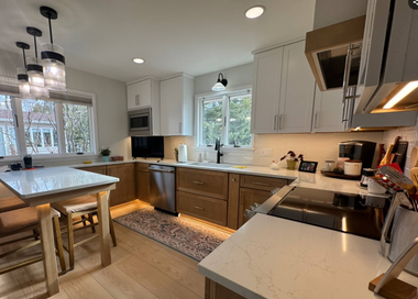 Bright modern kitchen with white cabinets, island, pendant lights, and wood accents