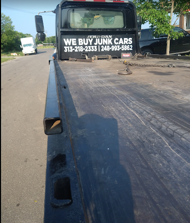 Tow truck on roadside with sign reading “We Buy Junk Cars” on the cab