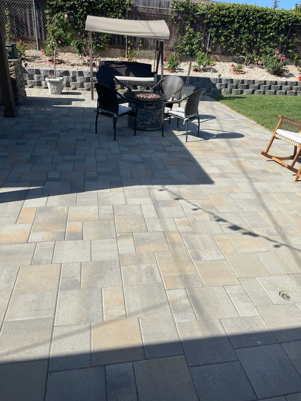 Patio with stone pavers, outdoor seating under an umbrella, and a grassy garden border.