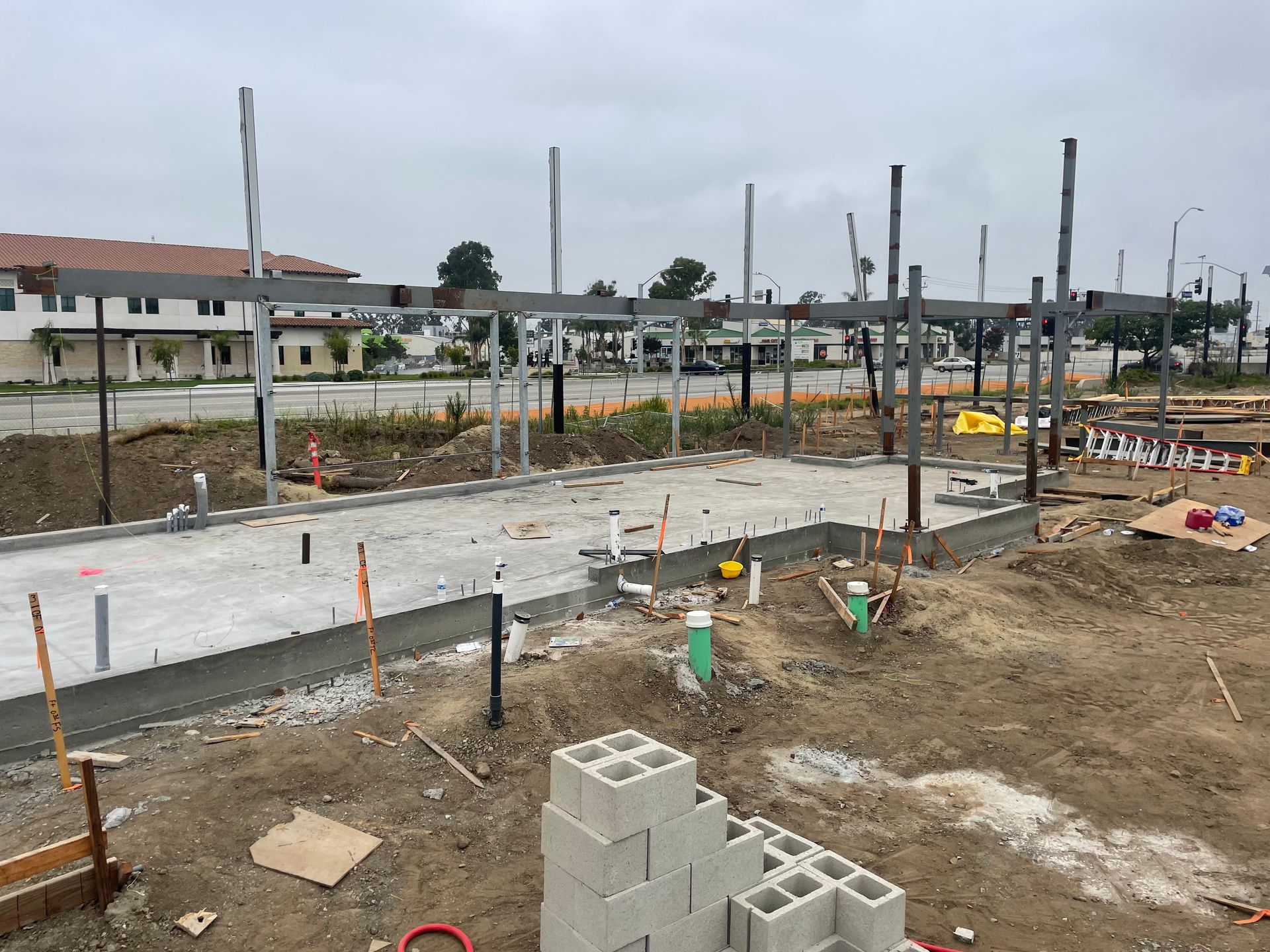 Construction site with concrete slab, rebar, and cinder blocks under overcast sky