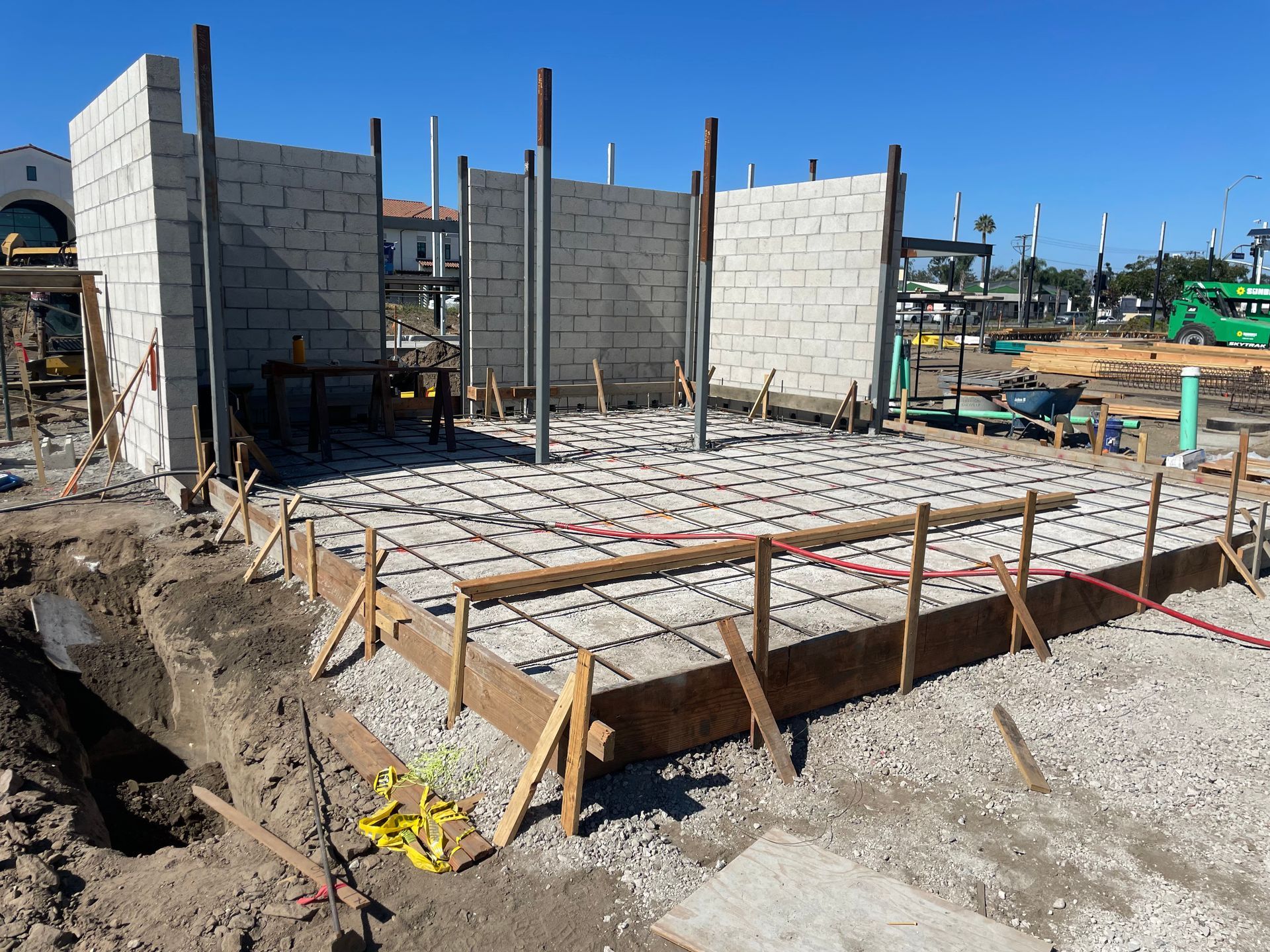 Partially built cinder block house with concrete floor and wooden forms at a construction site