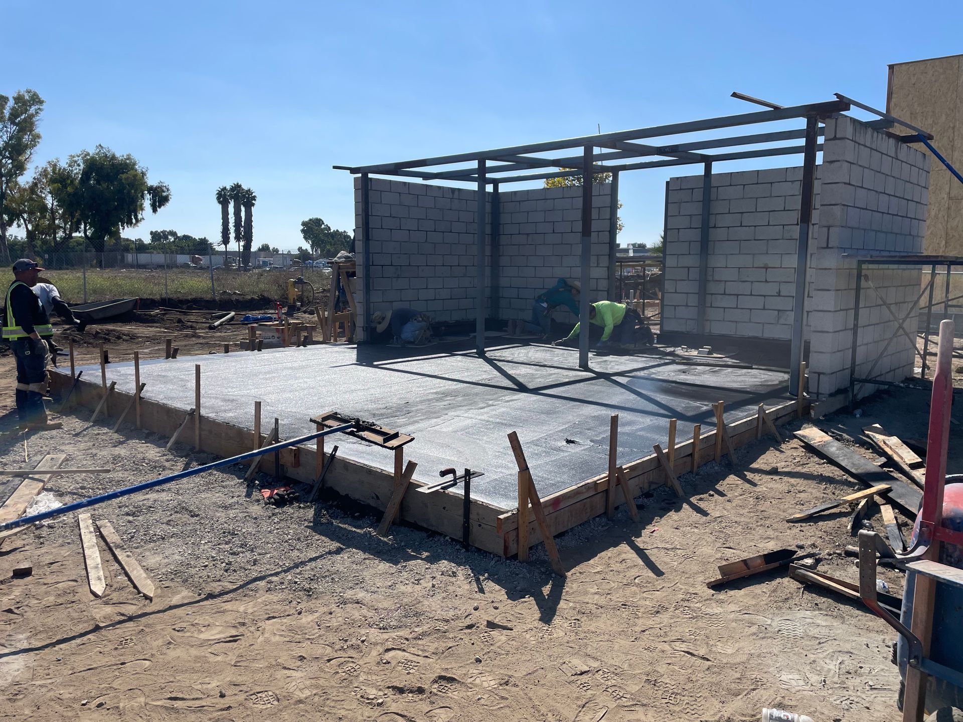 Partially built concrete slab and brick structure under construction in a dusty outdoor area