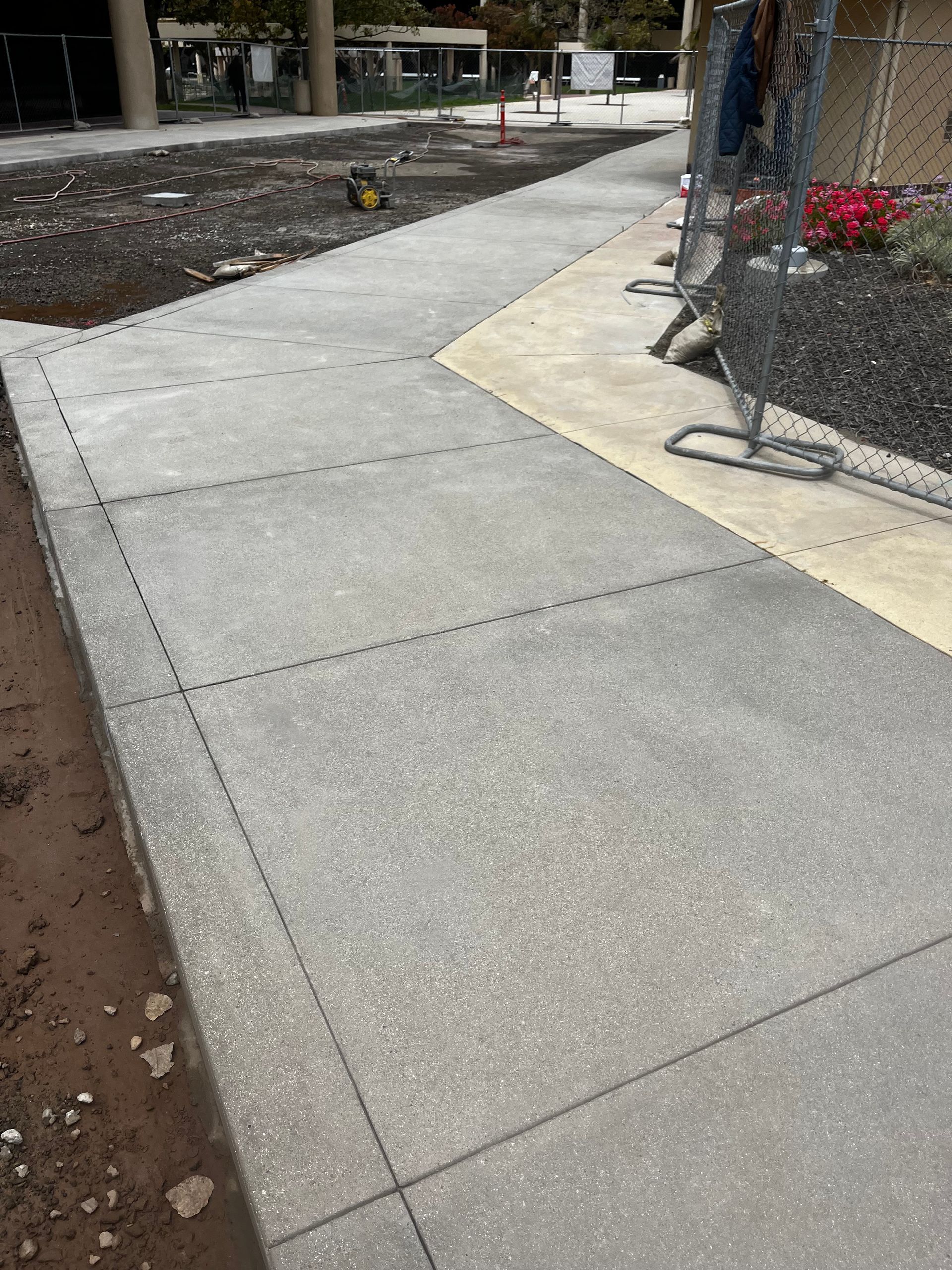 A concrete walkway leading to a house with a lush green lawn.