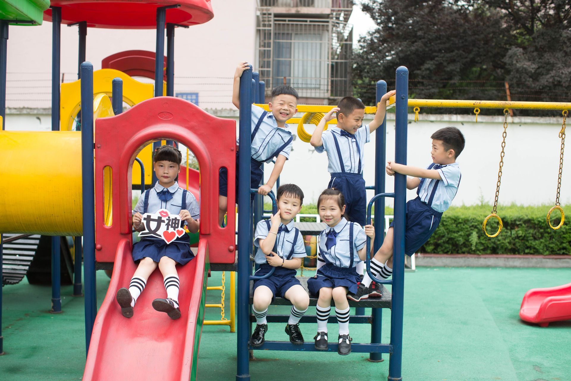 Children playing on a colorful playground slide and swing set outdoors.