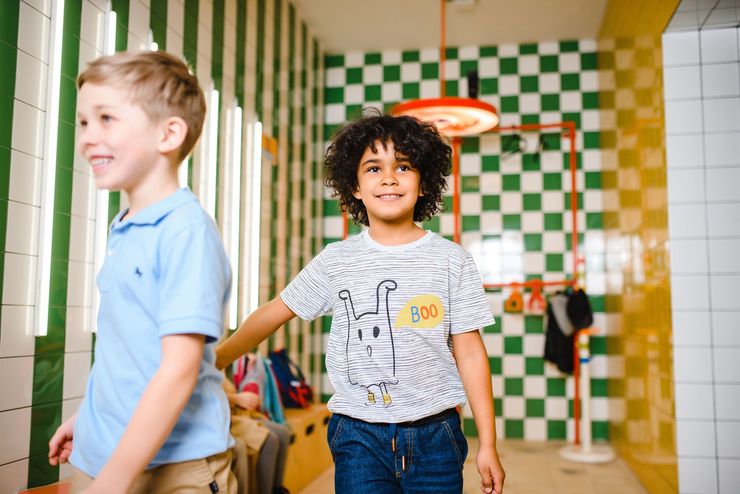 Children walking in a colorful school hallway with green-and-white tiled walls