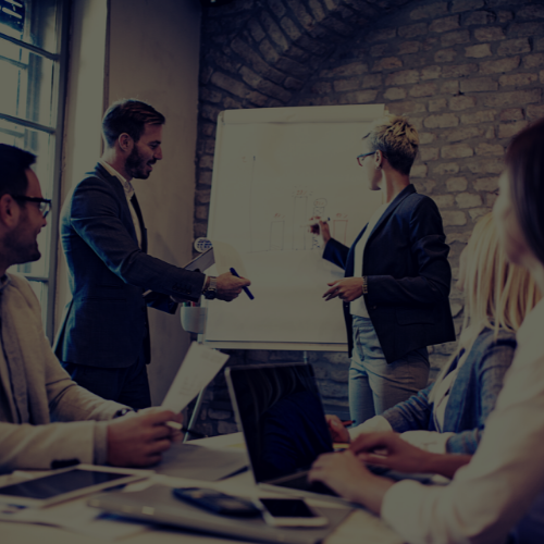 Business meeting with two presenters beside a whiteboard in a conference room