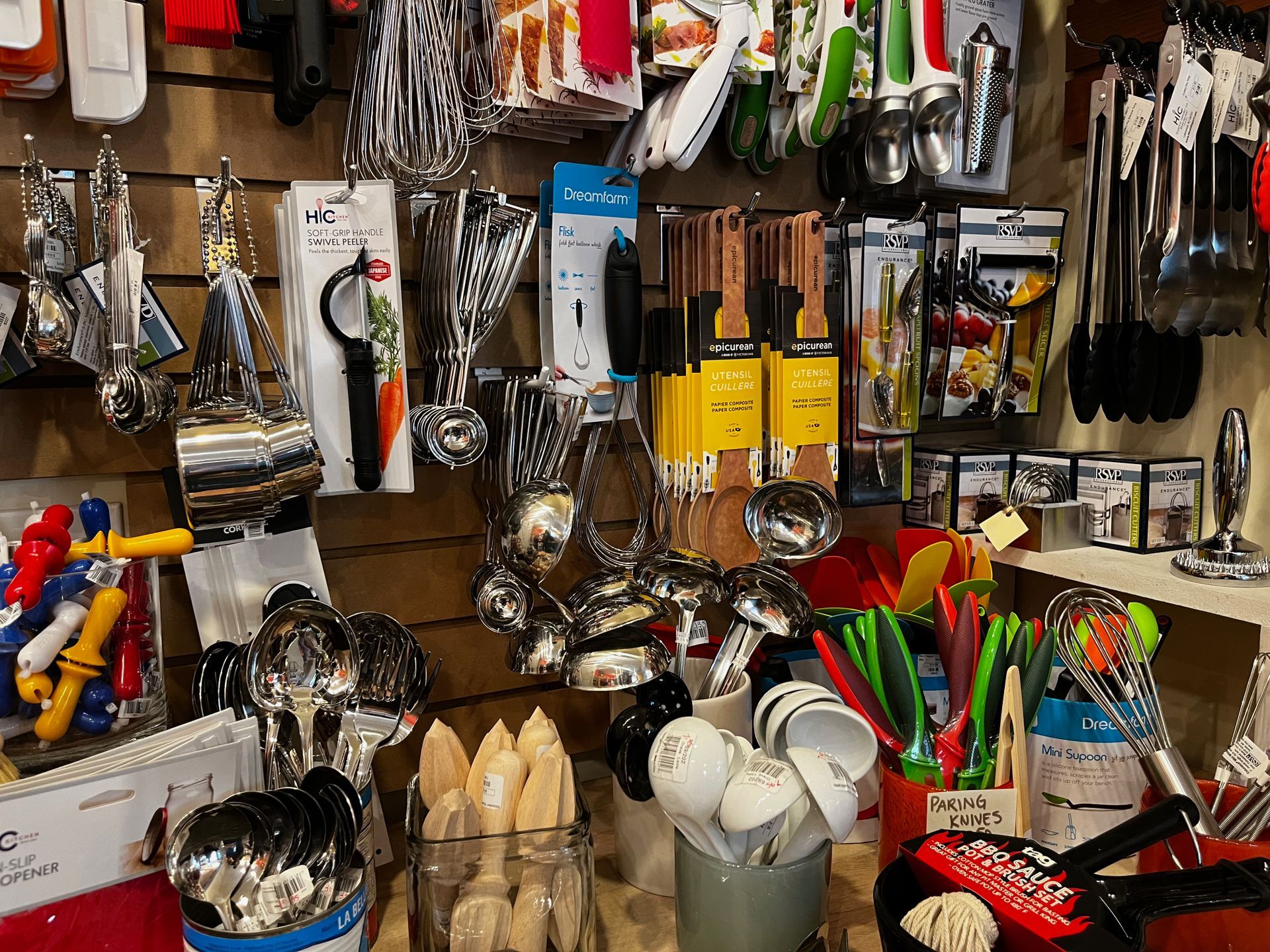 A bunch of kitchen utensils are hanging on a wall in a store.