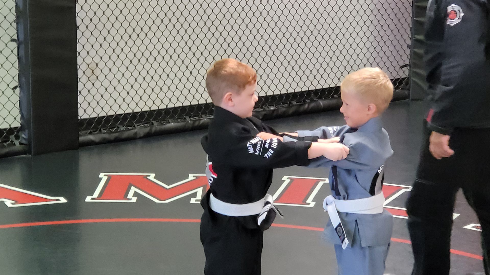 Two young boys are practicing martial arts in a gym