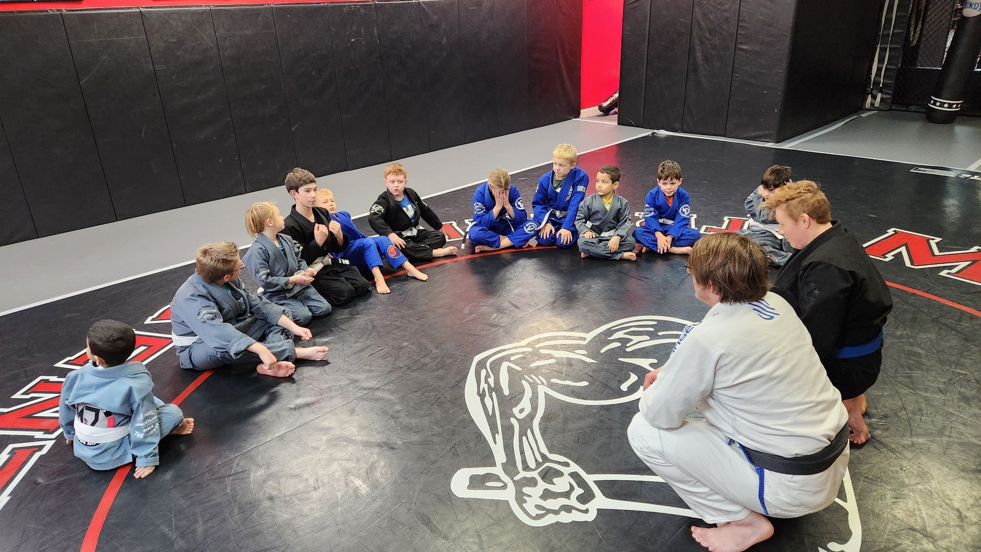 STudents at a Brazilian Jiu-Jitsu class, sitting on mat