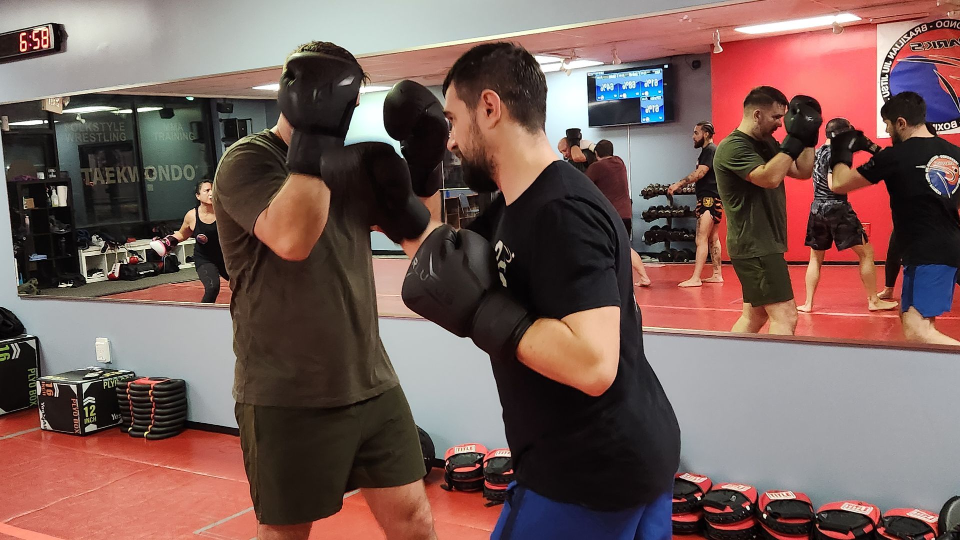 Two men are boxing in a gym in front of a mirror.
