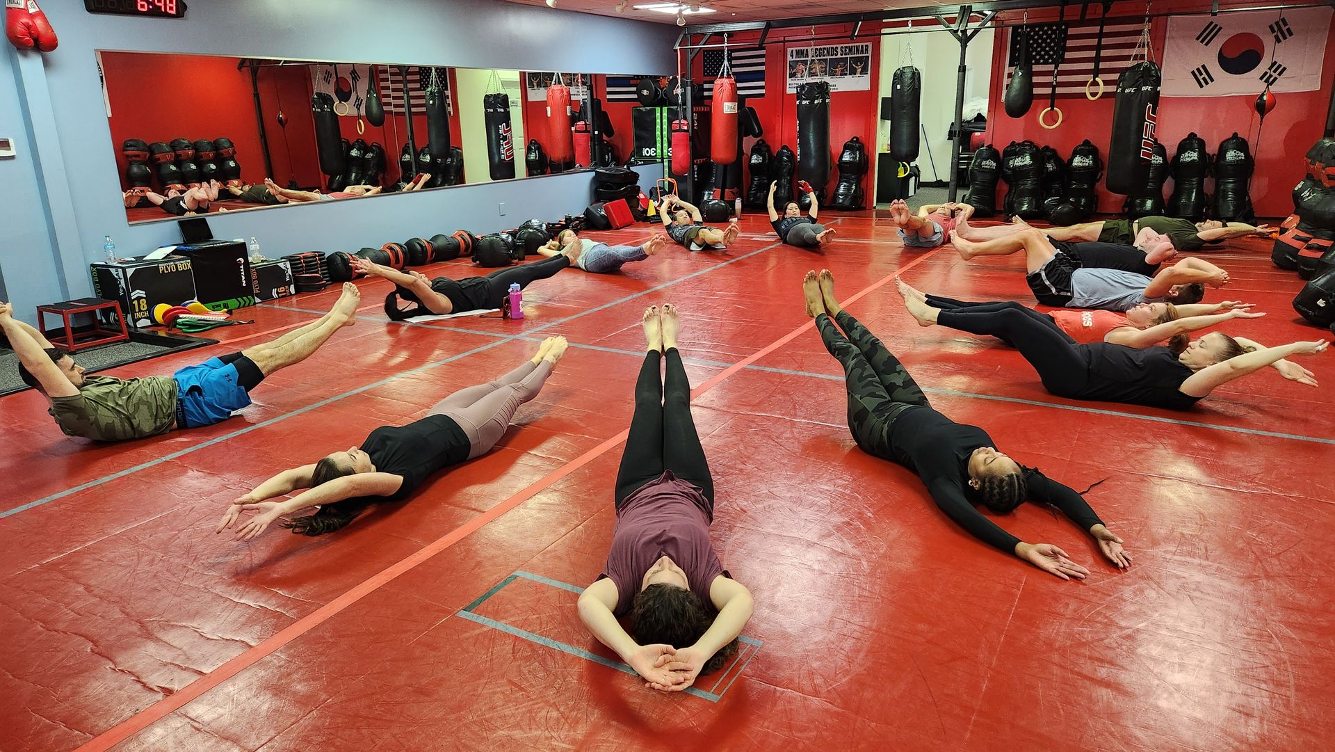 Three women are doing squats on yoga mats in a gym.