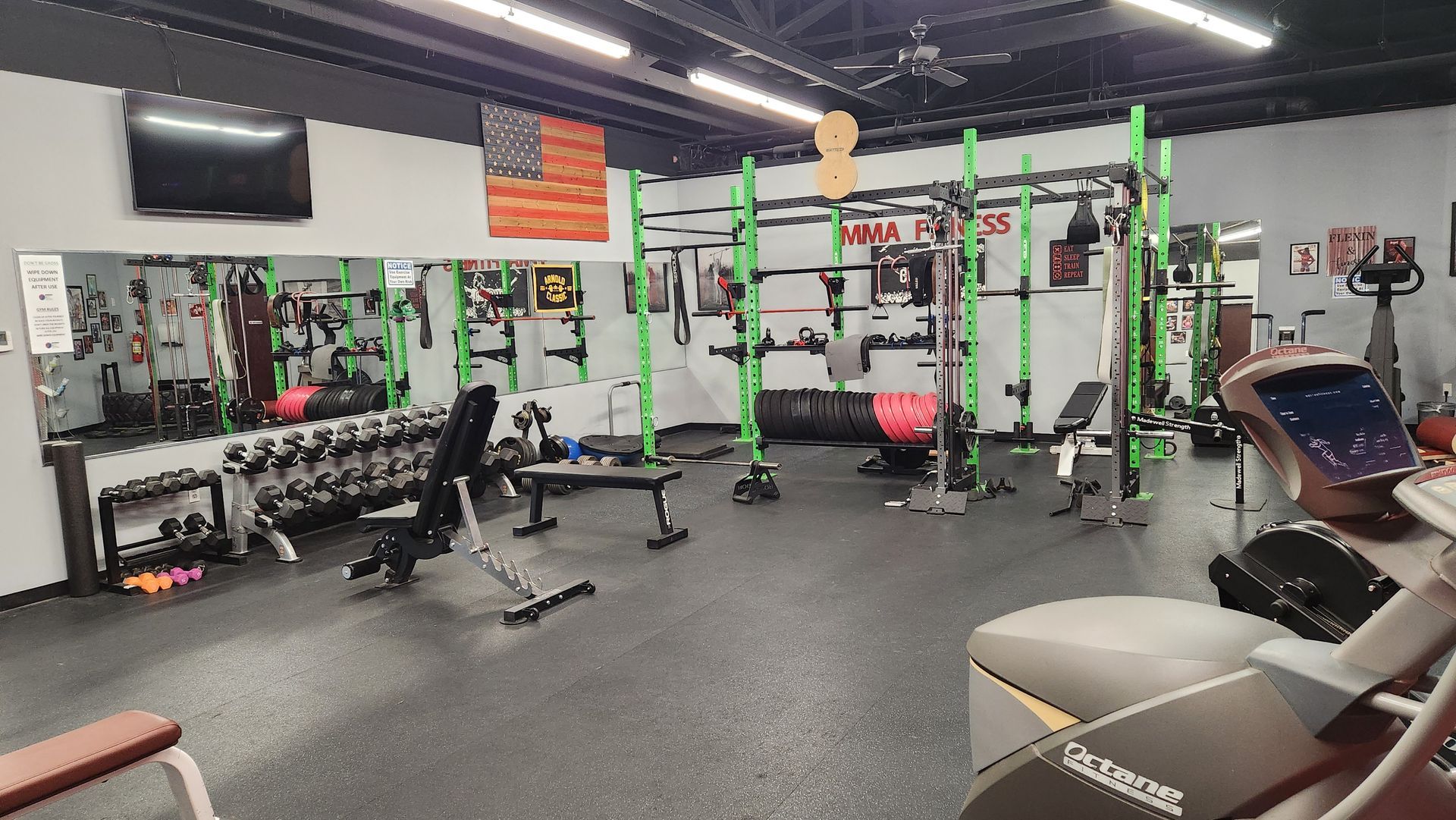 A gym with a lot of equipment and a tv on the wall.