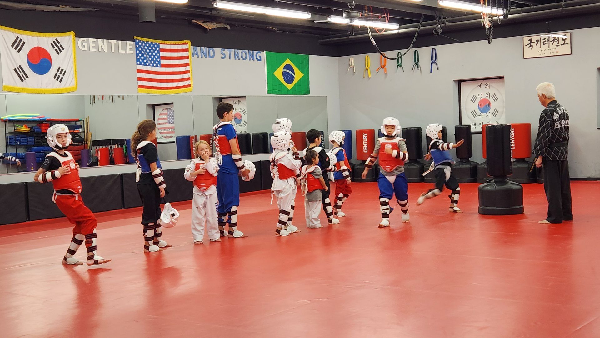 A group of children are practicing martial arts in a gym.