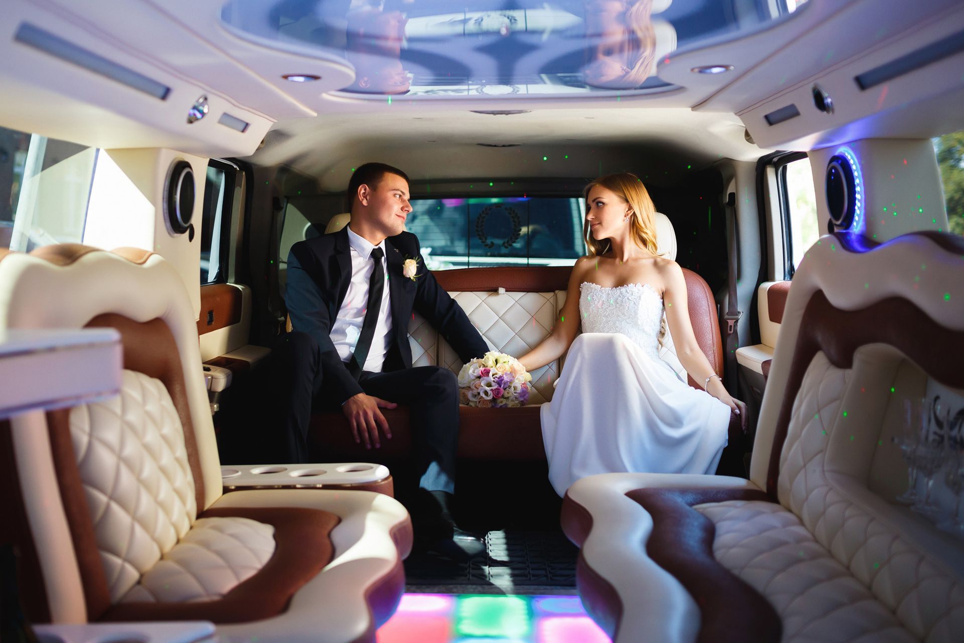 Bride and groom in a wedding limousine, holding hands