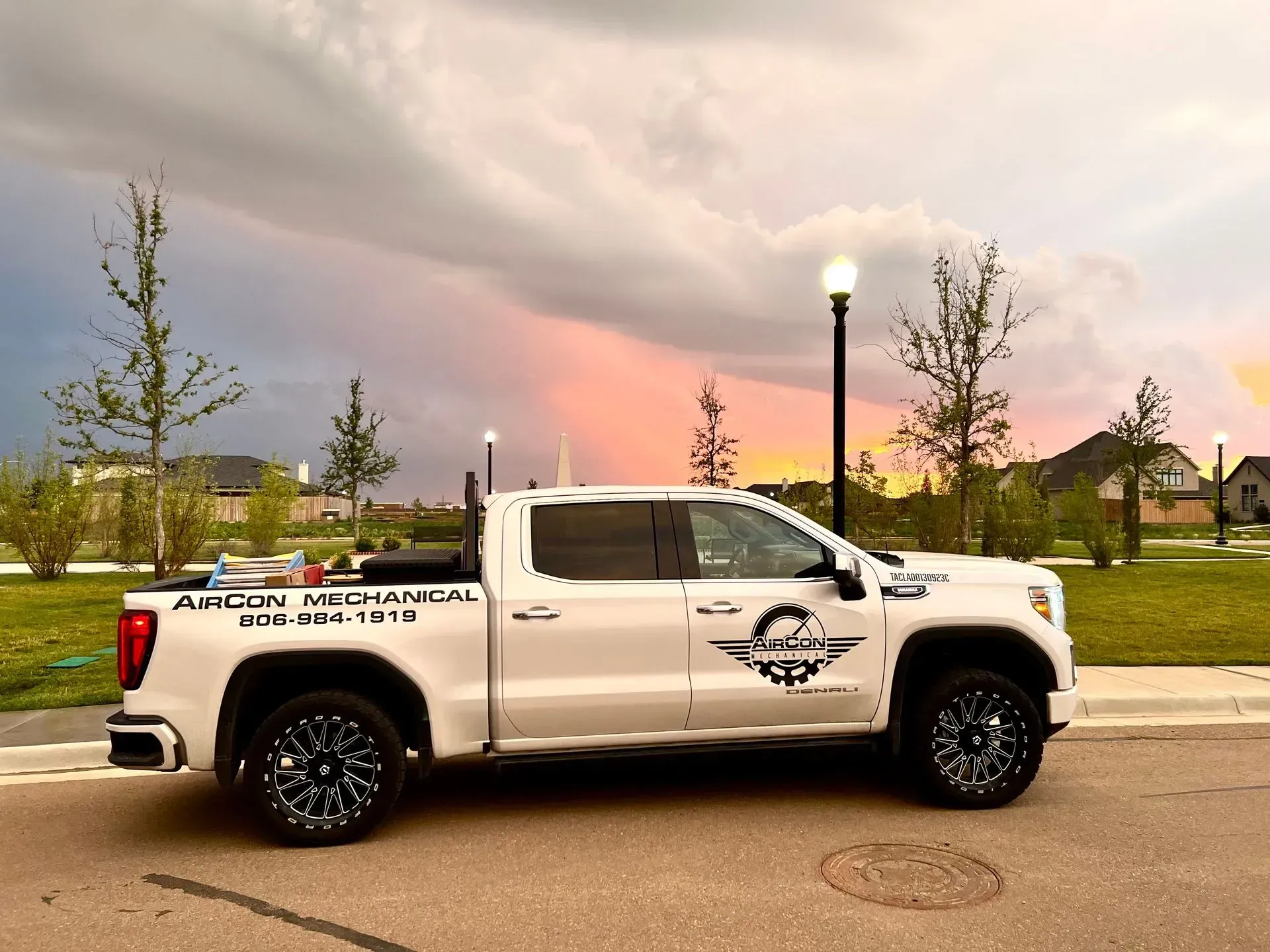 A white truck is parked on the side of the road in front of a park.