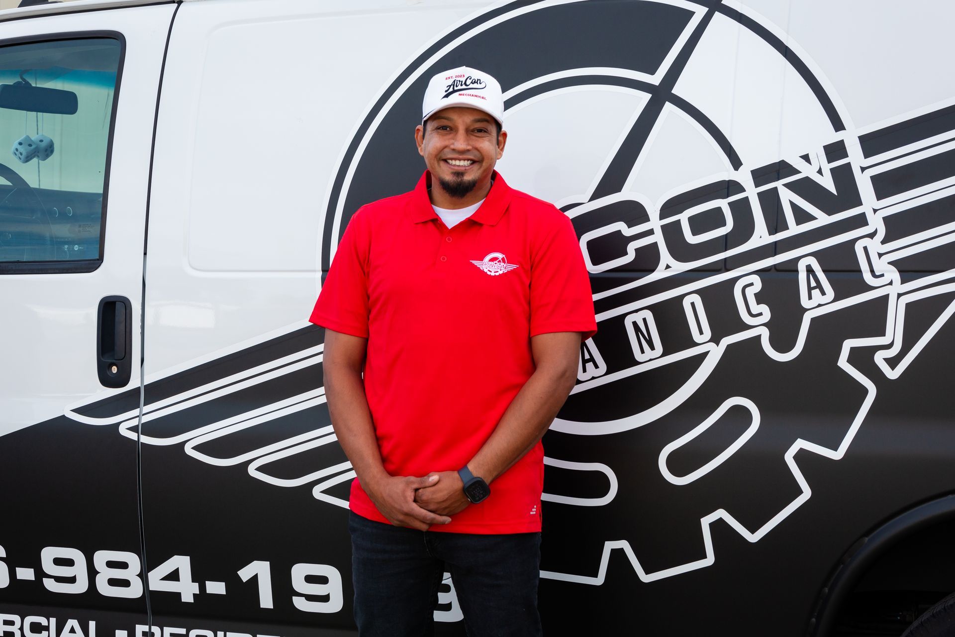 A man in a red shirt is standing in front of a van that says construction