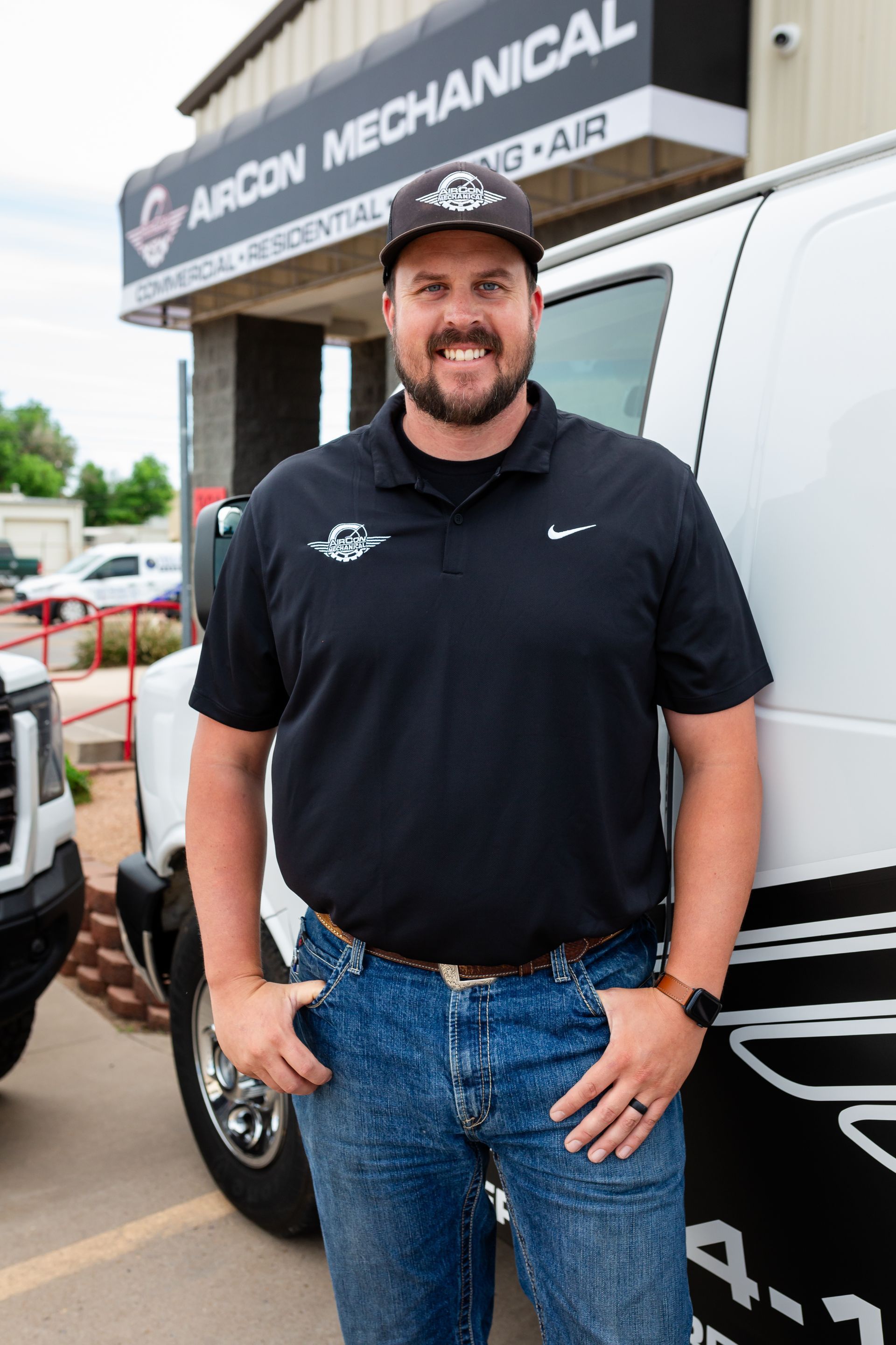 A man is standing in front of a van in a parking lot.