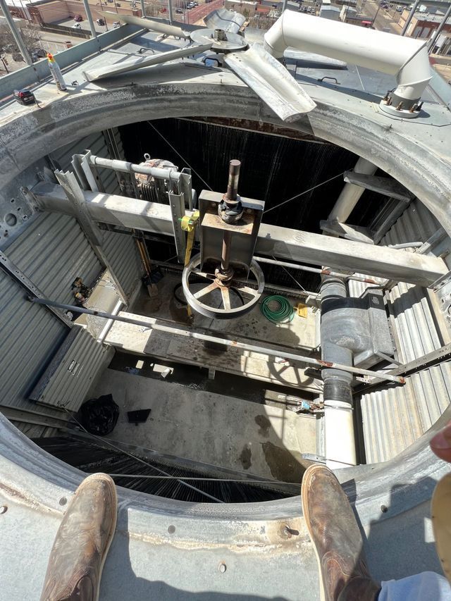 A person is standing on top of a building looking down at a machine.