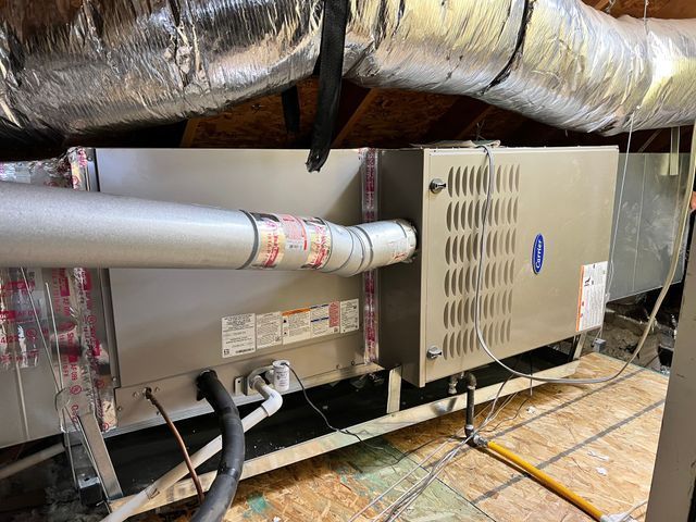 A large air conditioner is sitting in the attic of a house.