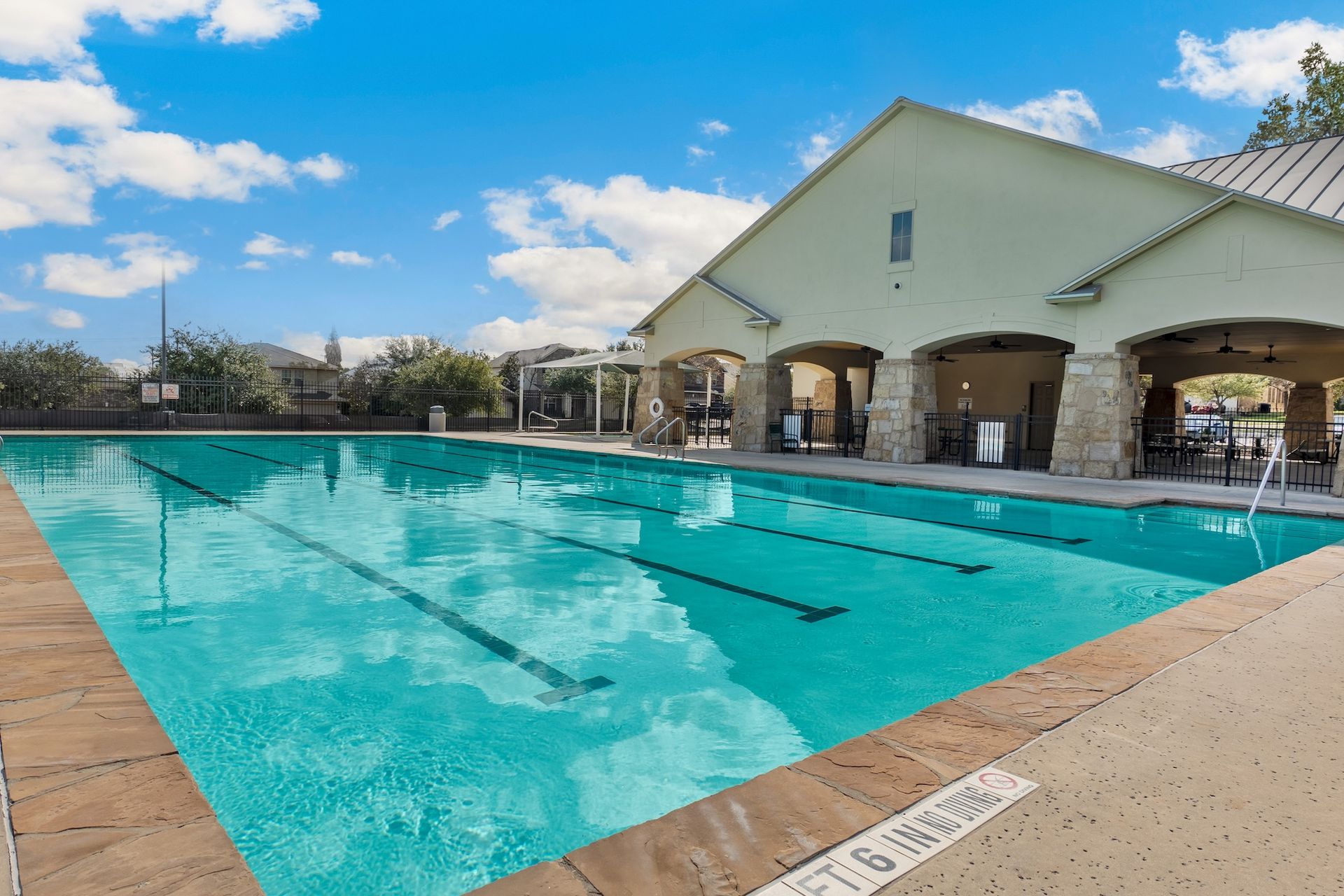Outdoor swimming pool beside a covered pavilion under a blue sky