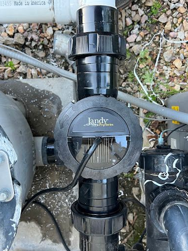 Black inline pool filter valve with a circular center opening on gravel outdoors