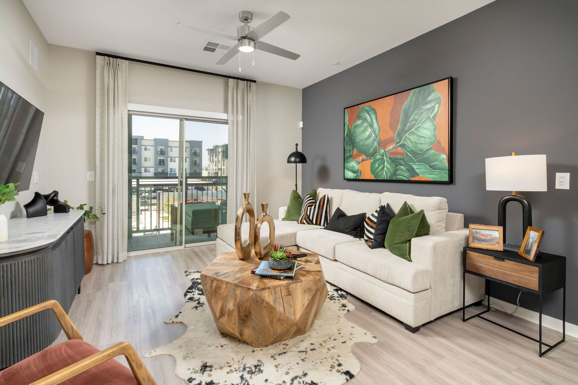 Modern living room in a beige and gray apartment with a sofa, coffee table, and balcony door.