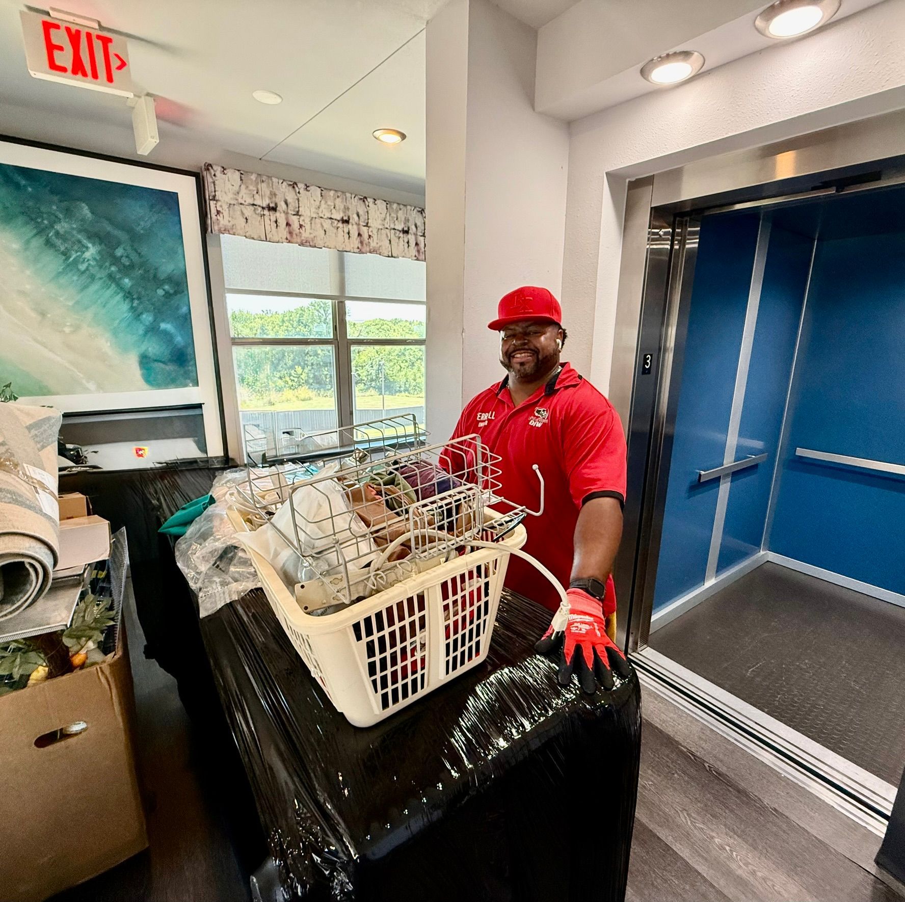 Man in red holding basket near elevator; prepping for move.